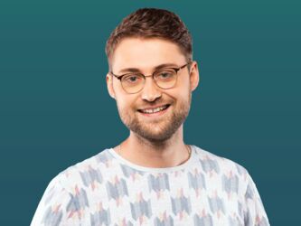 Bachelor-Student der Sozialversicherung mit Brille und Bart vor petrolfarbenem Hintergrund
