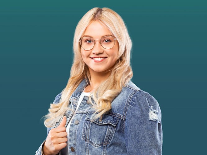 blonde junge Frau mit Brille und Jeansjacke lächelt ins Bild vor petrolfarbenem Hintergrund