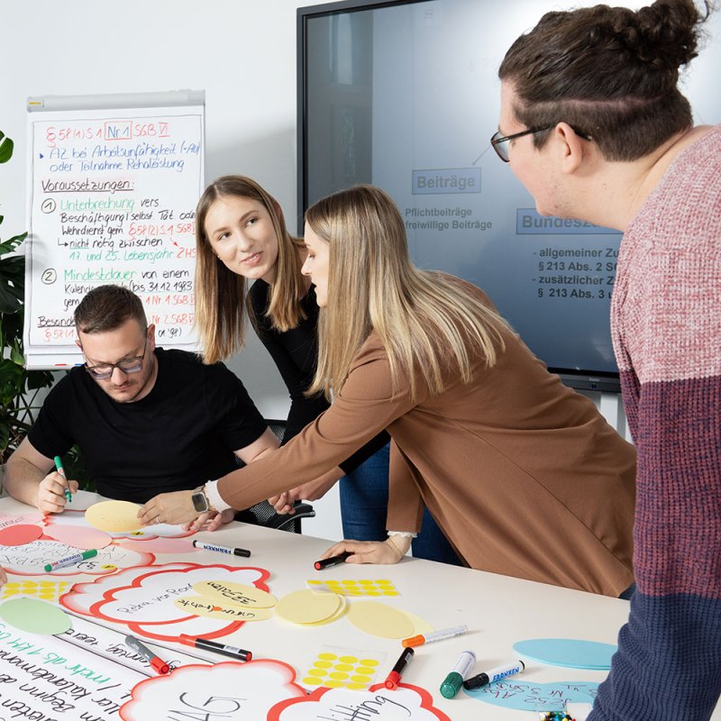 junge Menschen beschriften bunte Zettel und Plakate in der Gruppenarbeit