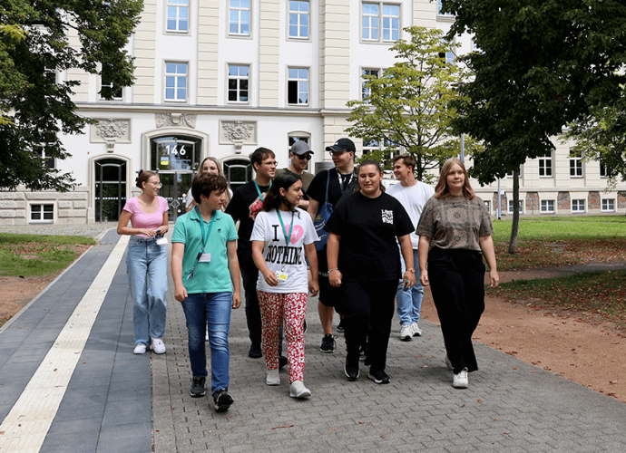 Eine Gruppe von zehn jungen Menschen entfernen sich zu Fuß von einem Bürogebäude.