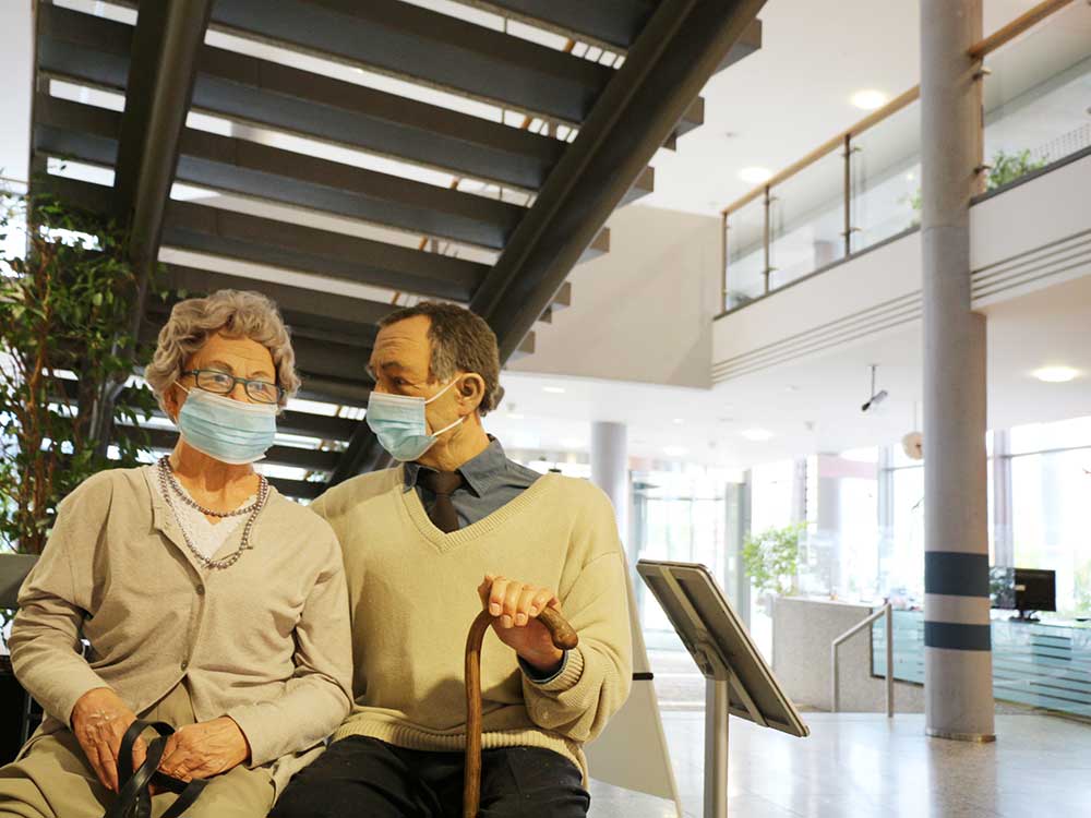 Figuren eines älteren Ehepaars mit Mund-Nasen-Schutz und Gehstock im Eingangsbereich der Deutschen Rentenversicherung in Erfurt