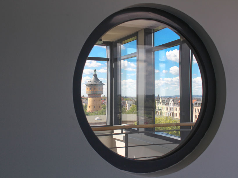 Blick durch Rundfenster der Deutschen Rentenversicherung Mitteldeutschland auf Hallenser Wasserturm