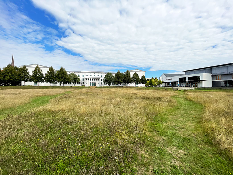 Wiese und im Hintergrund langgestreckter Hauptbau sowie Mensa mit Mehrzweckhalle der Hochschule Meißen